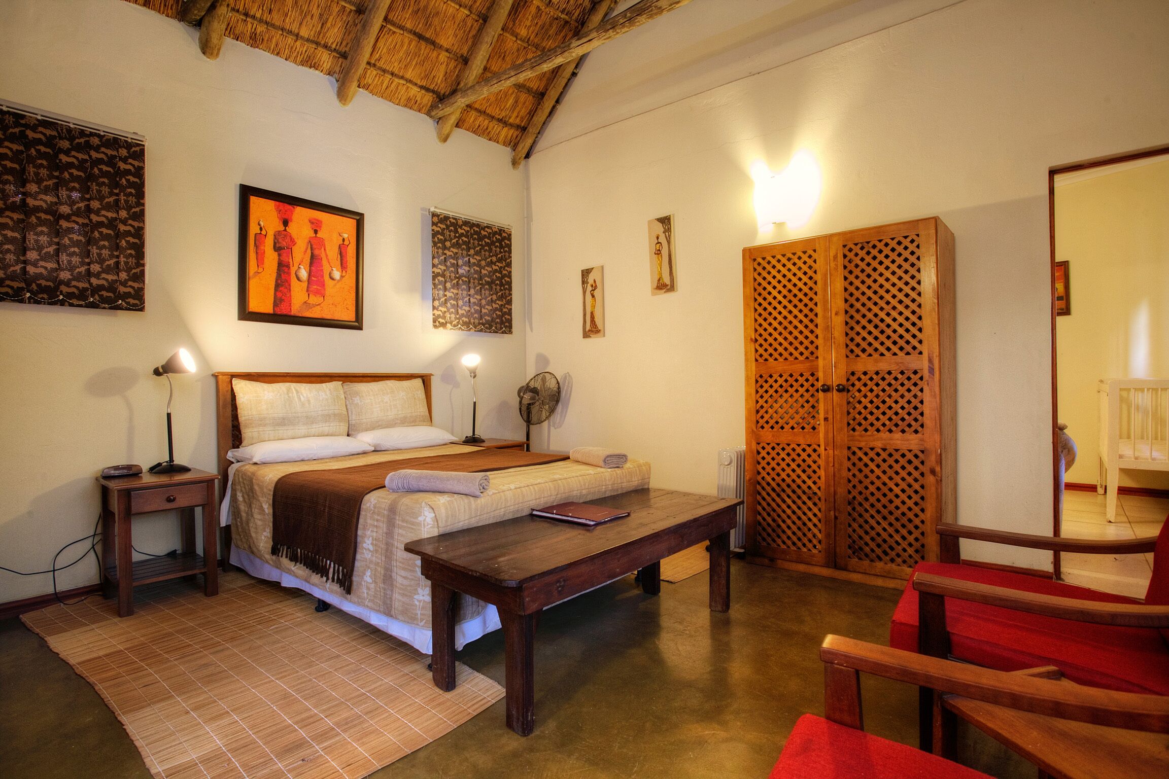 A room with a bed, bedside table, lamp, and a wooden wardrobe.