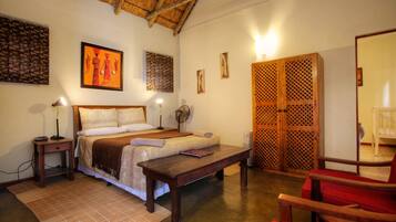 A room with a bed, bedside table, lamp, and a wooden wardrobe.