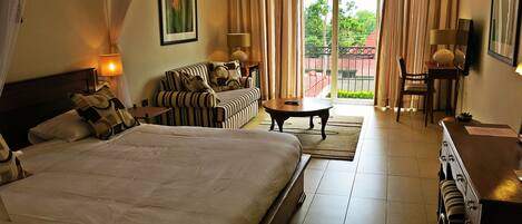 Una habitación de hotel con una cama grande, un sofá, una mesa de centro y un escritorio.