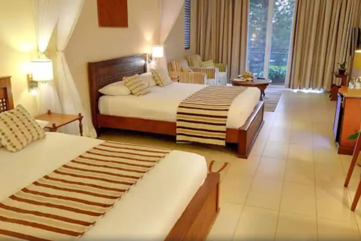 A hotel room with two beds, a desk, and a chair.