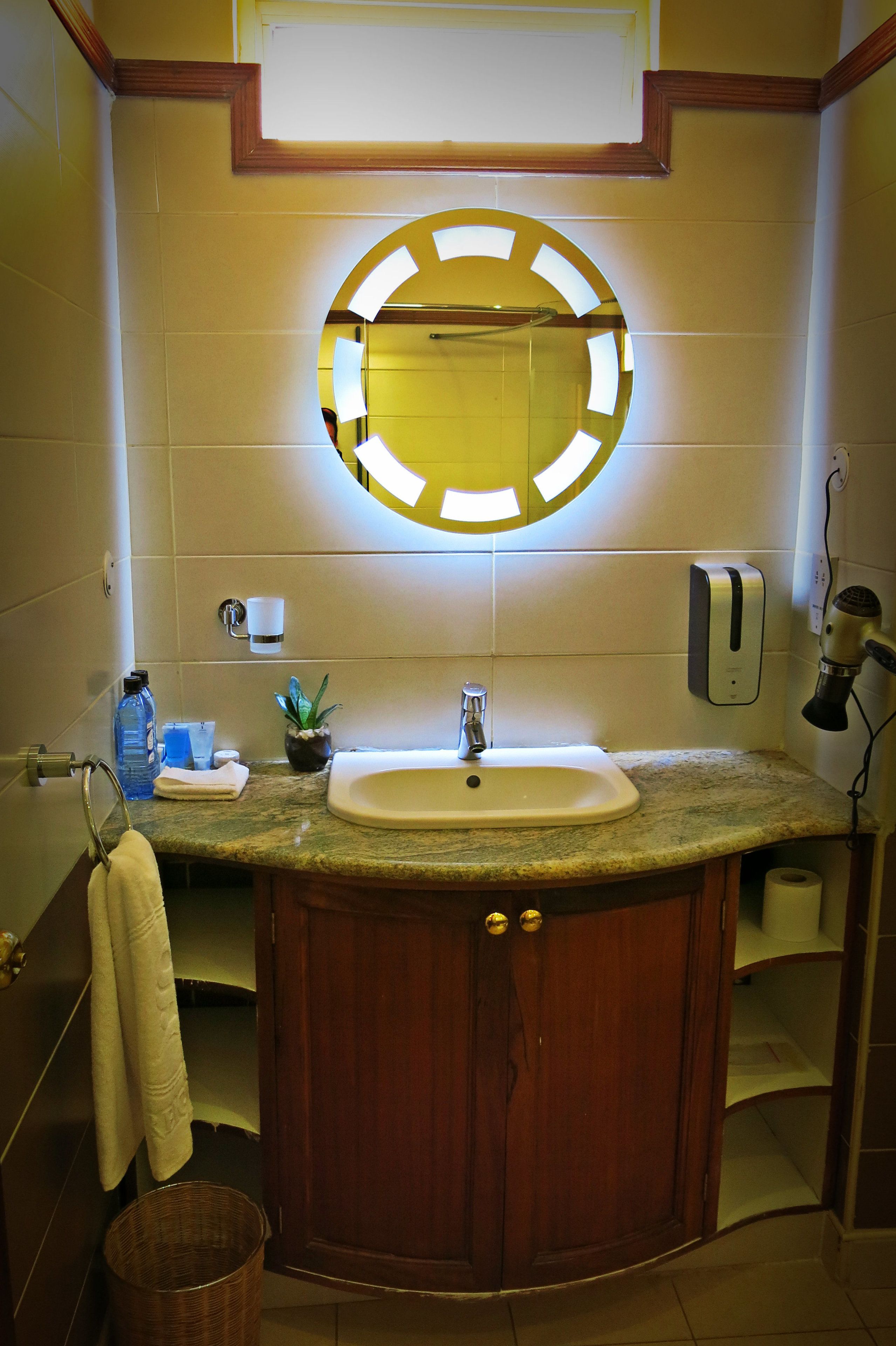 A bathroom with a sink, mirror, towel rack, and a hand dryer.