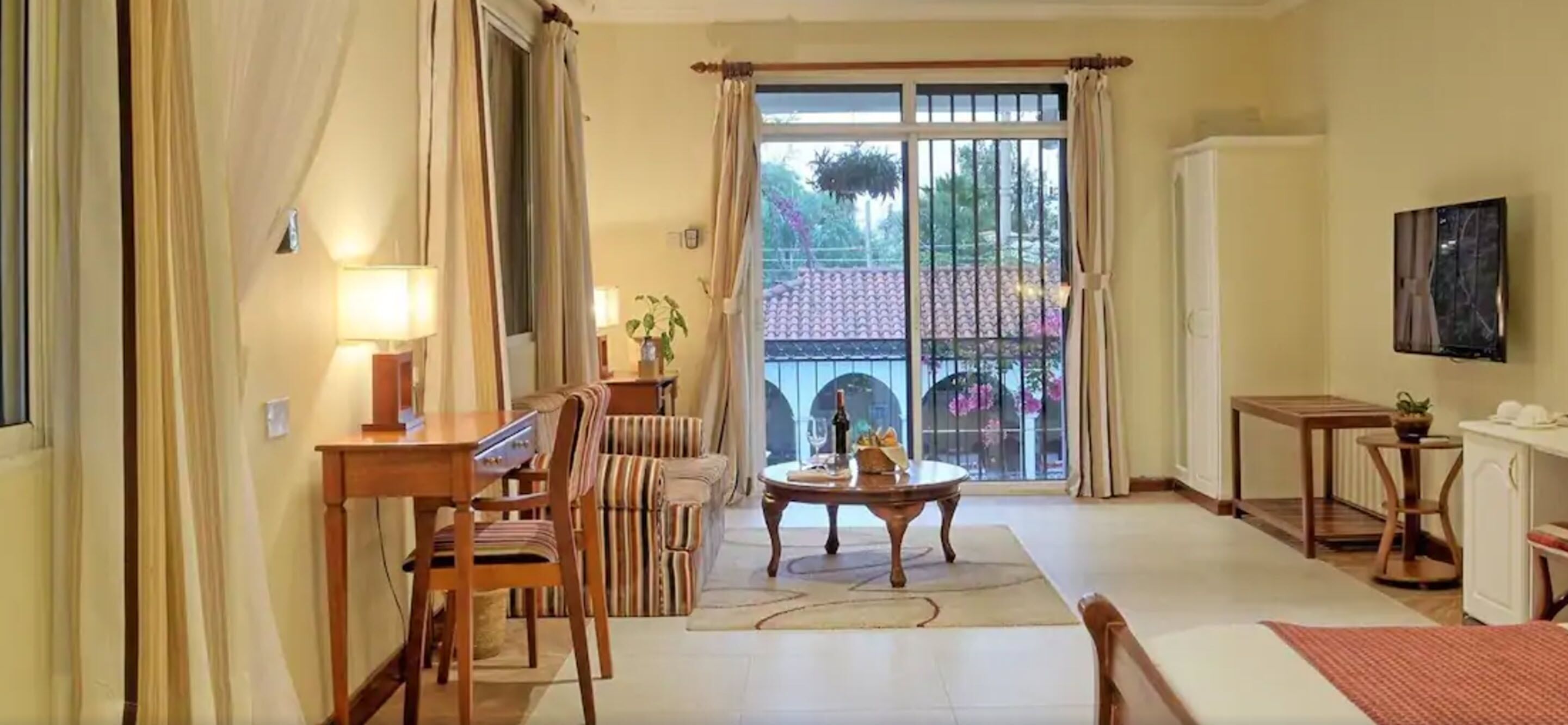 Un amplio salón con una mesa de comedor, sillas, un sofá, una mesa baja y un televisor montado en la pared.
