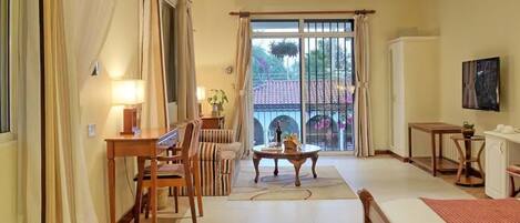 Un amplio salón con una mesa de comedor, sillas, un sofá, una mesa baja y un televisor montado en la pared.