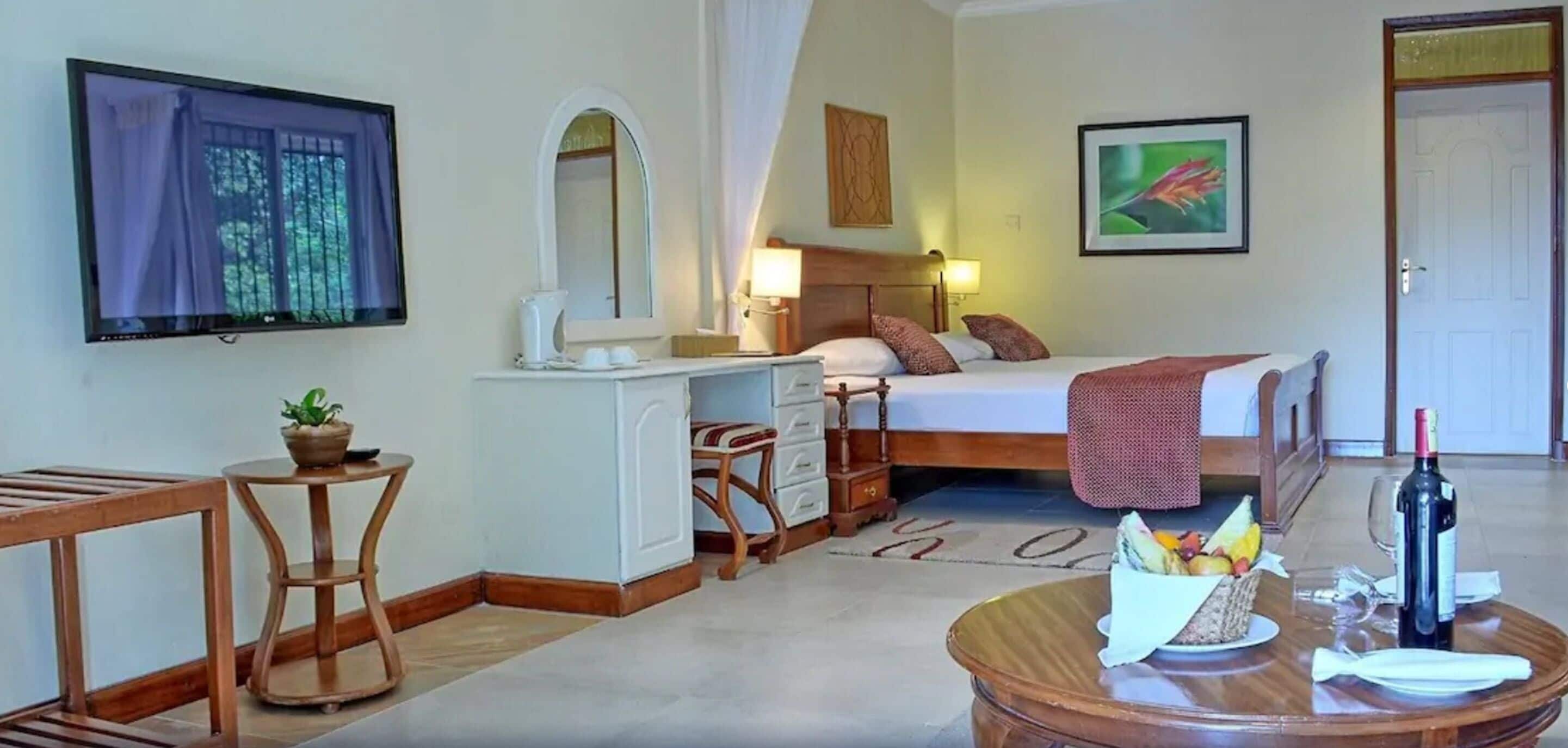 Een hotelkamer met een bed, bureau, stoel en een eettafel met eten en drinken.