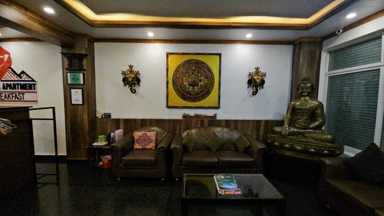 A living room with a sofa, a coffee table, a Buddha statue, and a wall-mounted emblem.