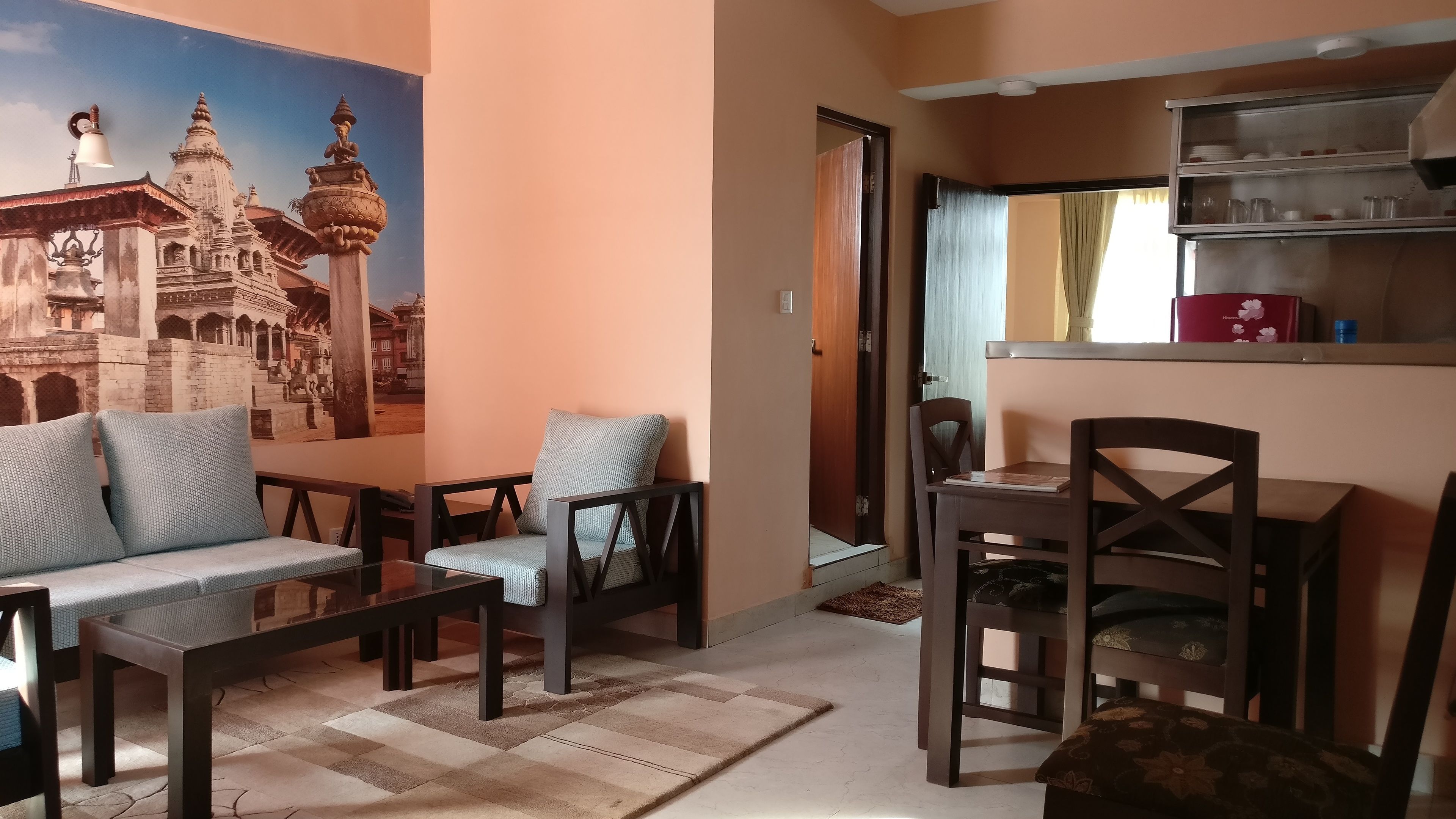 A living room with a sofa, chairs, a coffee table, and a wall mural of a temple.
