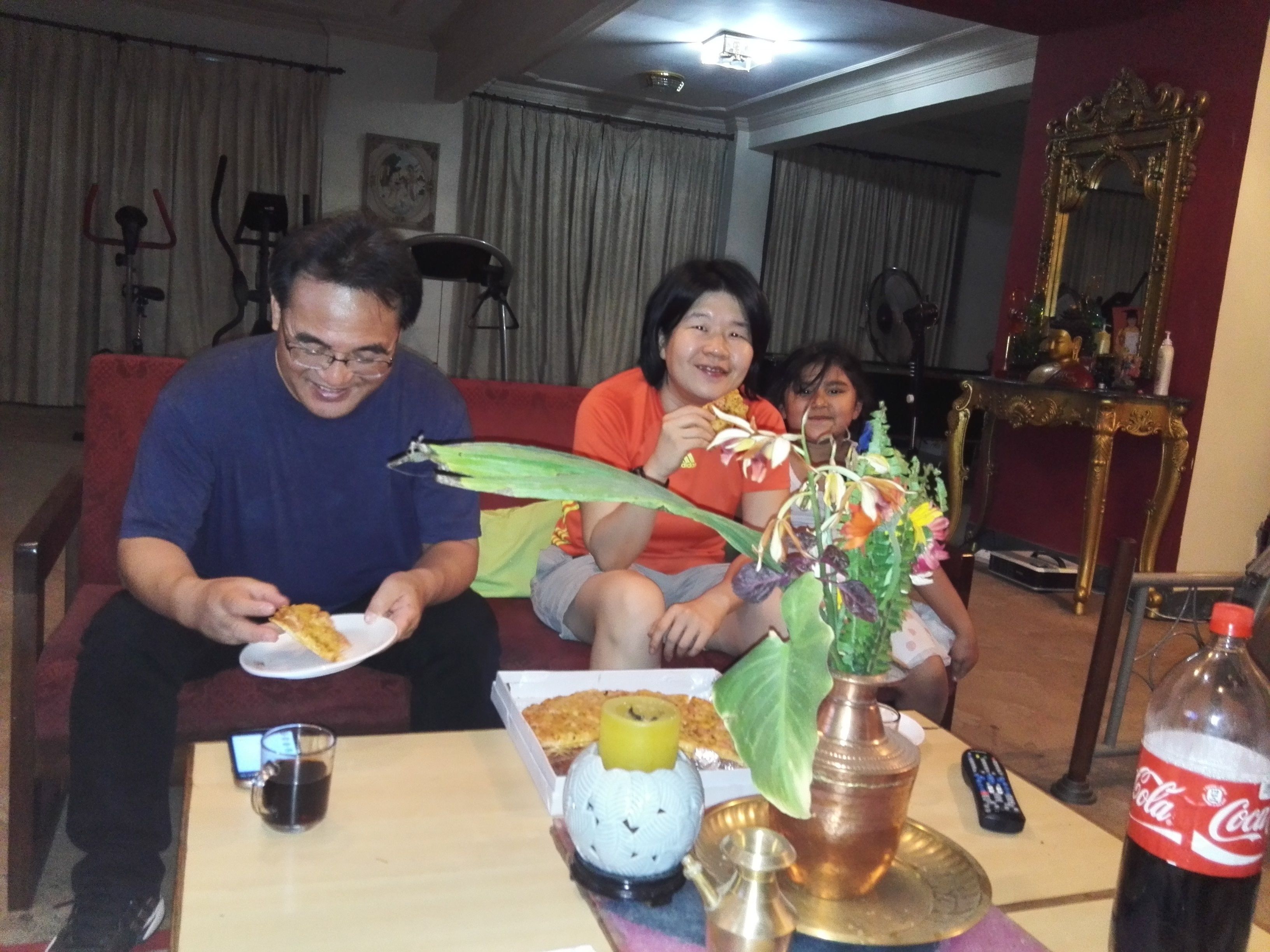 A living room with a red couch, a table with food and drinks, and a decorative vase.