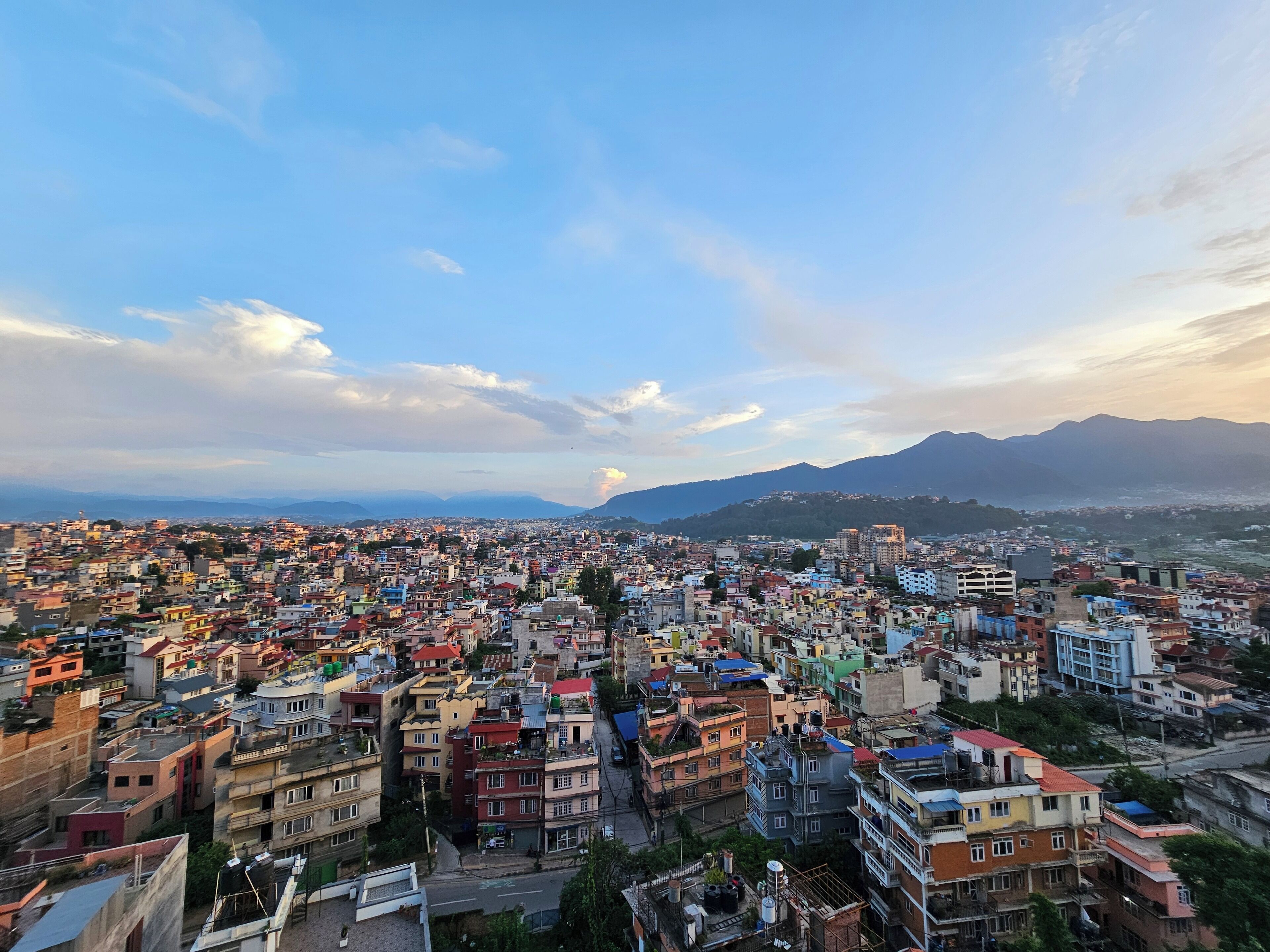 A densely packed urban area with a variety of building styles and colors, under a clear sky with scattered clouds.