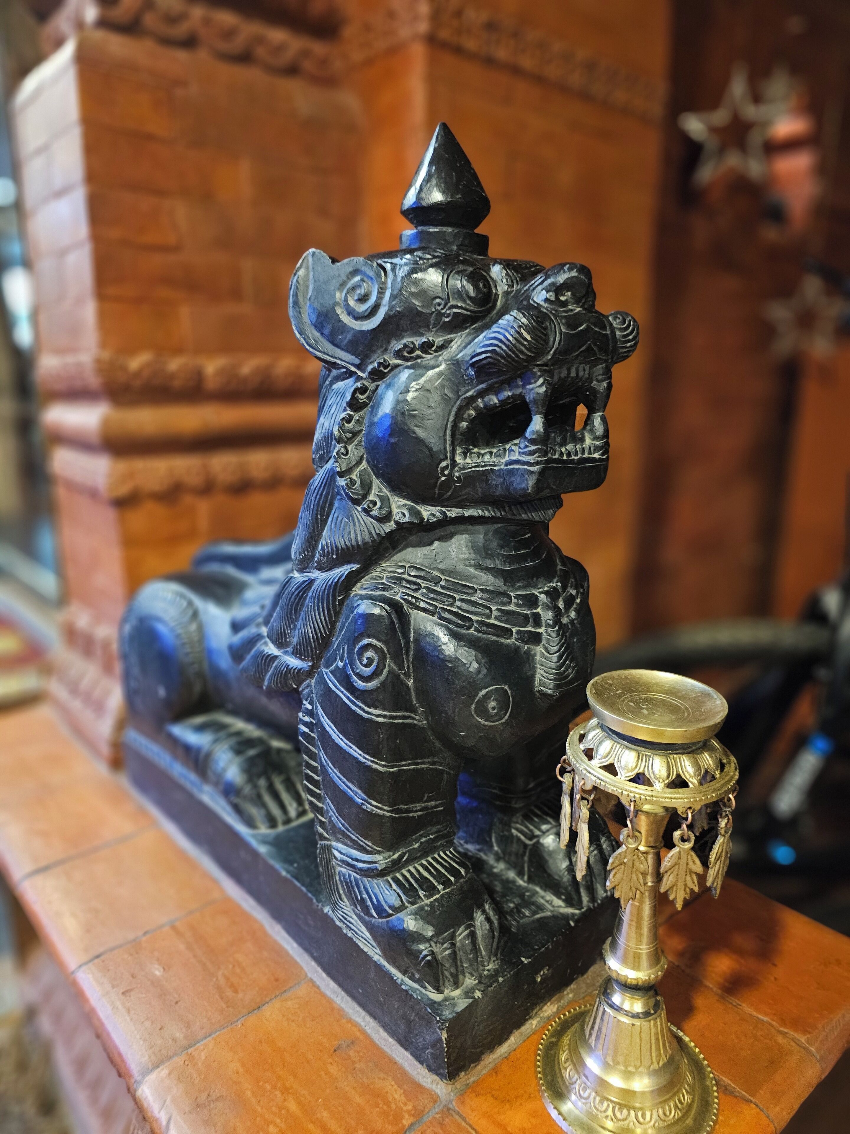 Una estatua de león con detalles tallados y una lámpara de latón a su lado.