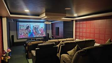A home theater room with a large screen, multiple seating areas, and a red patterned wall.