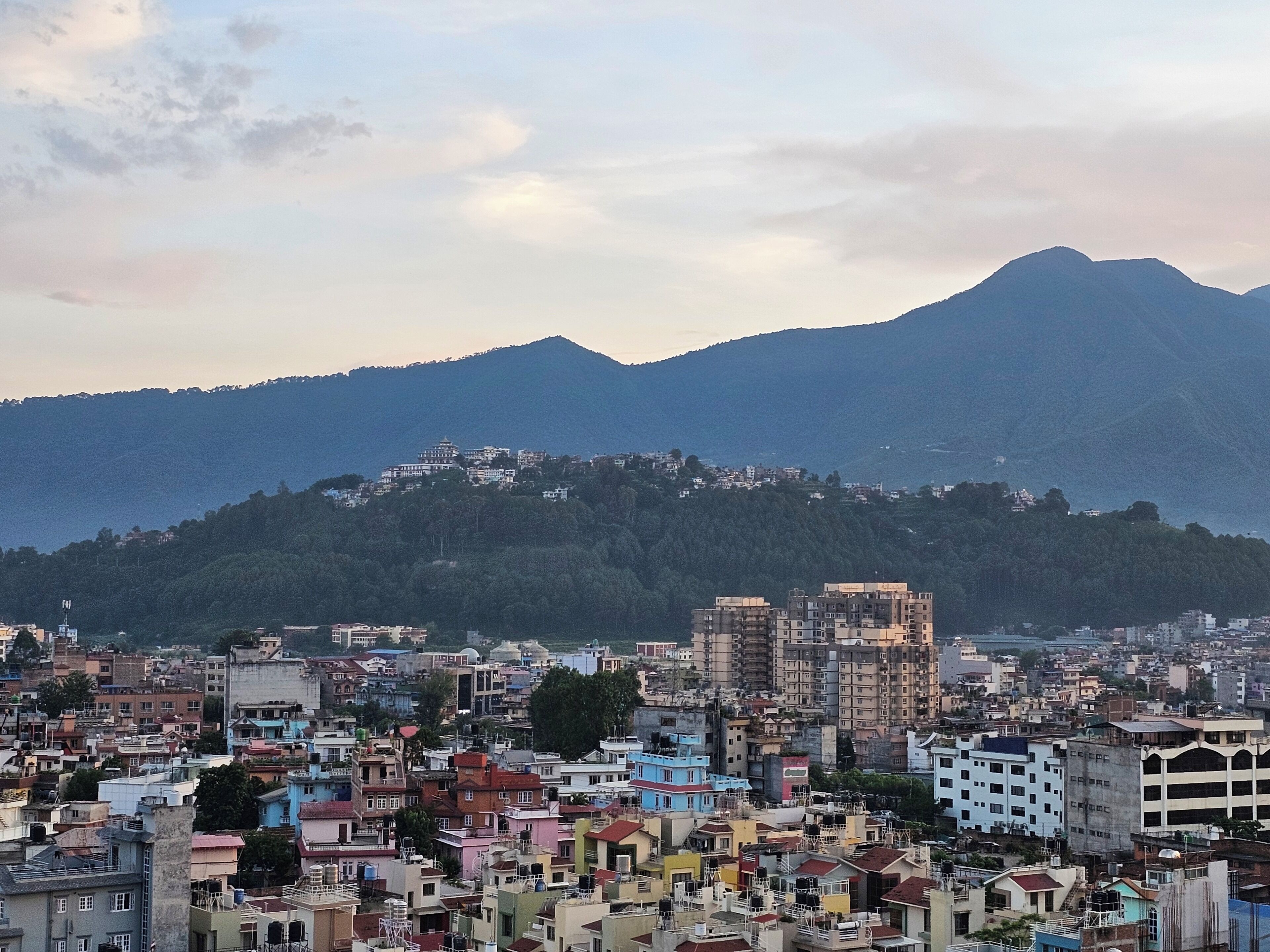A cityscape with buildings and a mountain in the background.