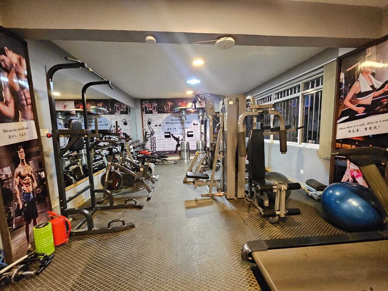 Una palestra con diverse attrezzature per l'allenamento, tra cui tapis roulant, macchinari per pesi e una voglia.