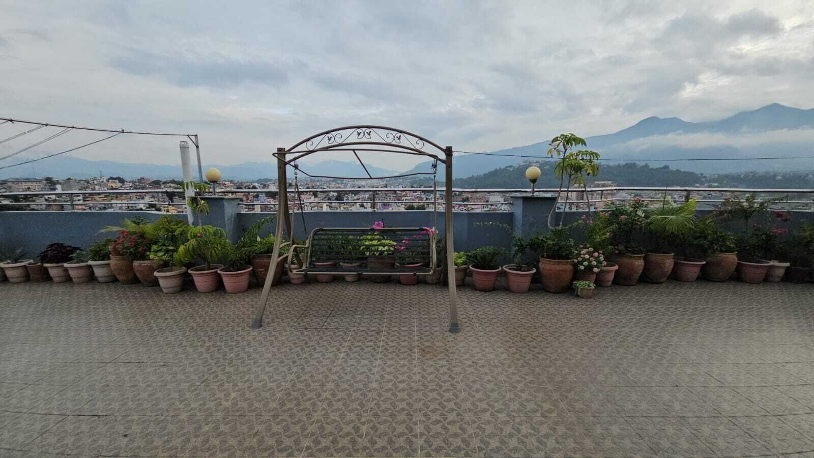 Une terrasse sur le toit, agrémentée d’une arche en métal, de plantes en pot et d’un banc.
