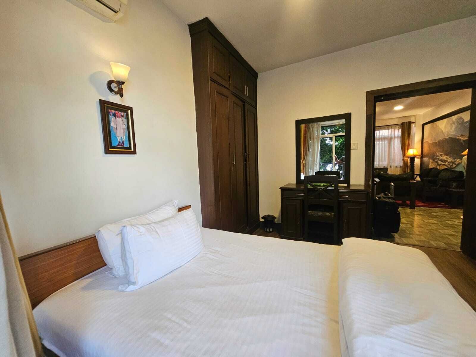 Habitació d'hotel amb un llit gran, un escriptori amb cadira, un armari i un mirall.