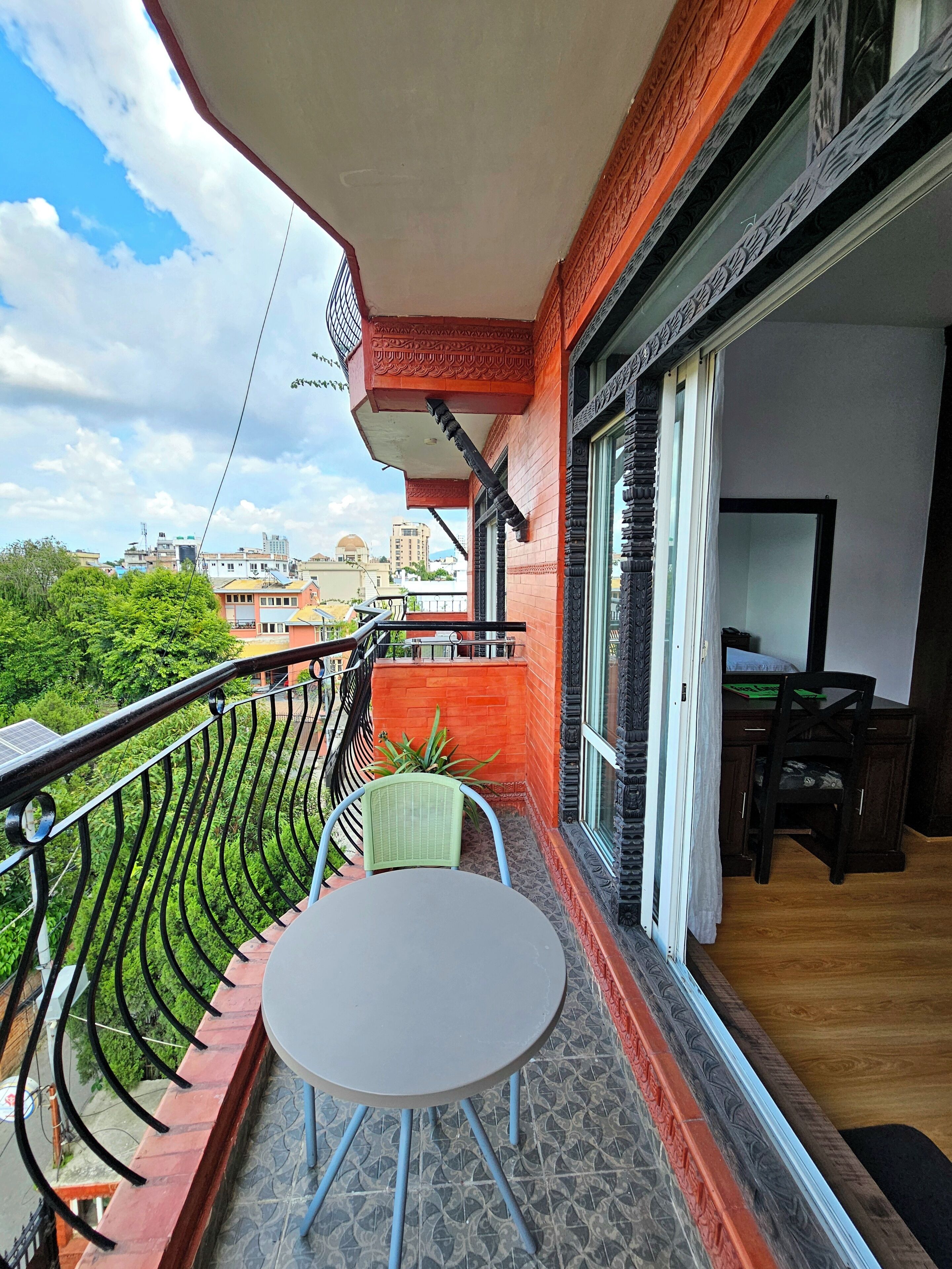 A balcony with a table and chairs, a view of the cityscape, and a door leading to an interior space.
