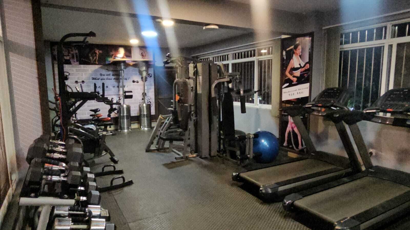 Un gimnasio con cintas de correr, máquinas de pesas y pelotas de ejercicio.