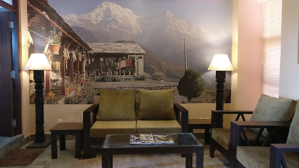 Un salón acogedor con un sofá, sillones y una mesa de centro. Un gran mural de un paisaje montañoso adorna la pared detrás de la zona de estar.