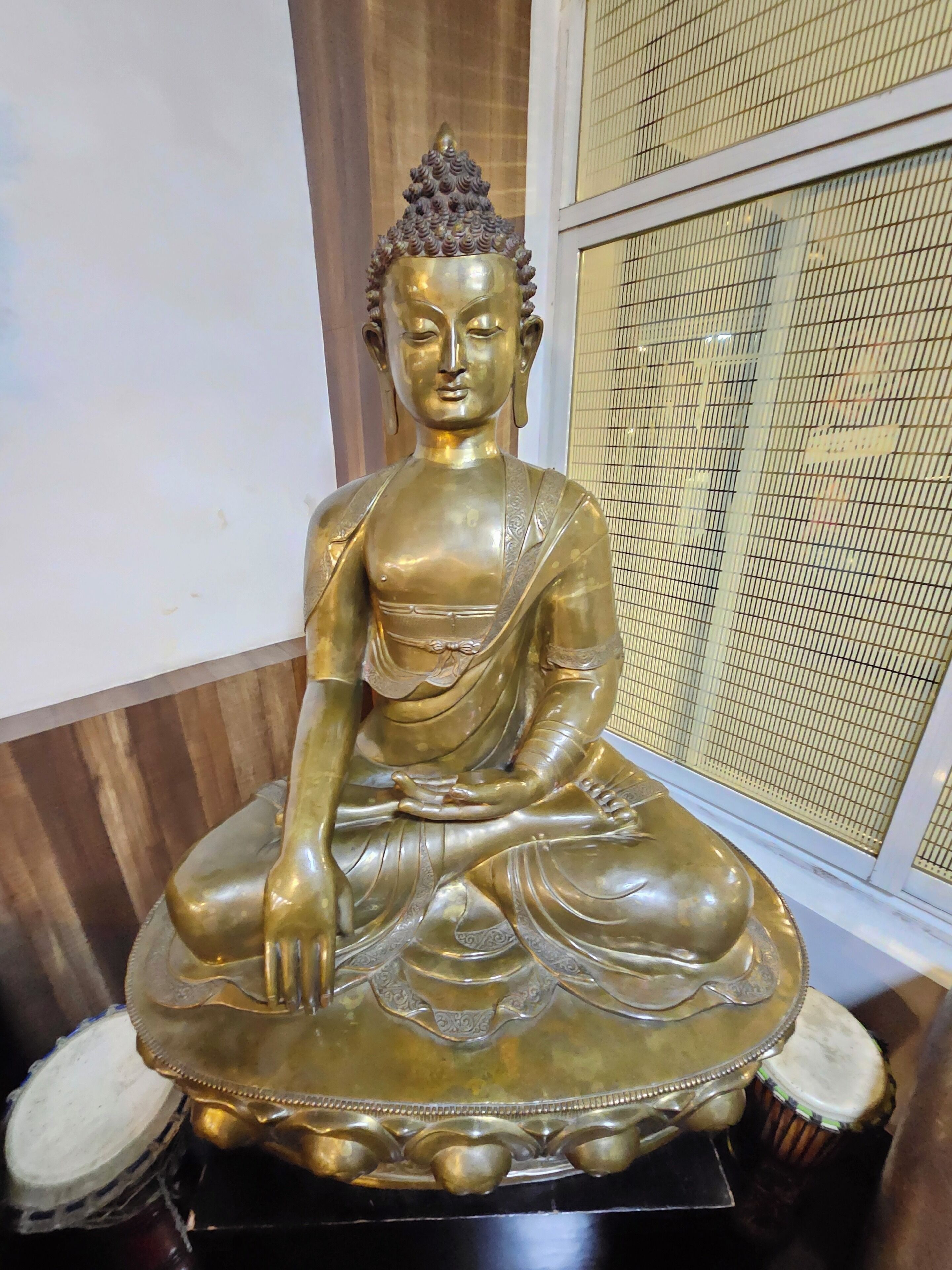 A seated Buddha statue with intricate details, placed on a pedestal.