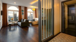 Un salon moderne avec un canapé, une table basse et une vue sur la ville grâce à de grandes fenêtres.