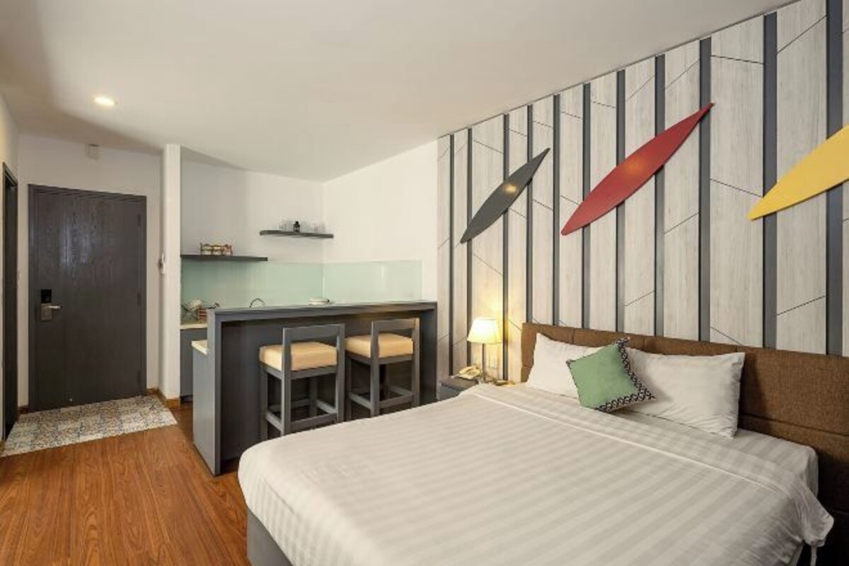 A hotel room with a bed, a desk, and a kitchenette.
