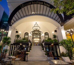 L’entrée du boutique-hôtel LeHouse, avec son grand escalier, son lustre et son espace salon extérieur.