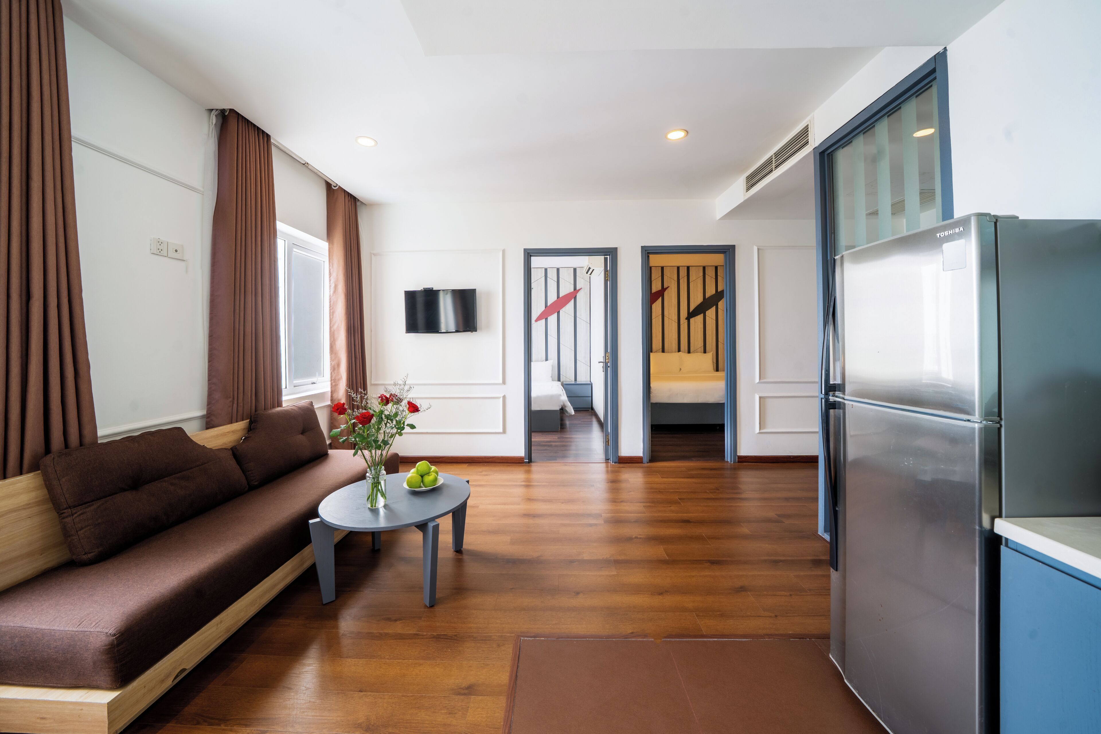 A modern living room with a sofa, a small table with a vase, and a refrigerator.