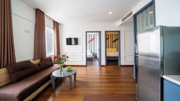 A modern living room with a sofa, a small table with a vase, and a refrigerator.