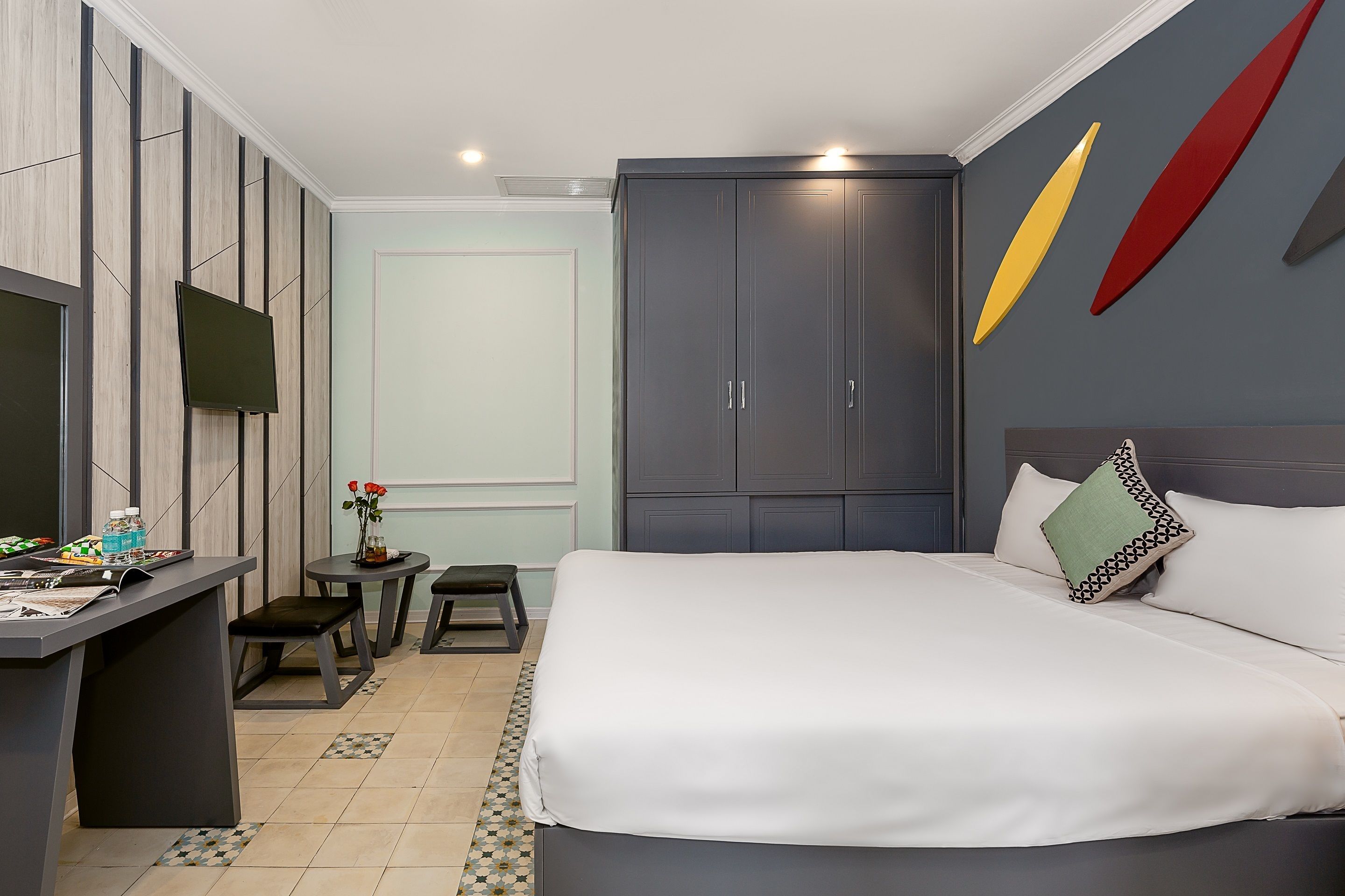 A modern hotel room with a bed, a desk, and a wardrobe.