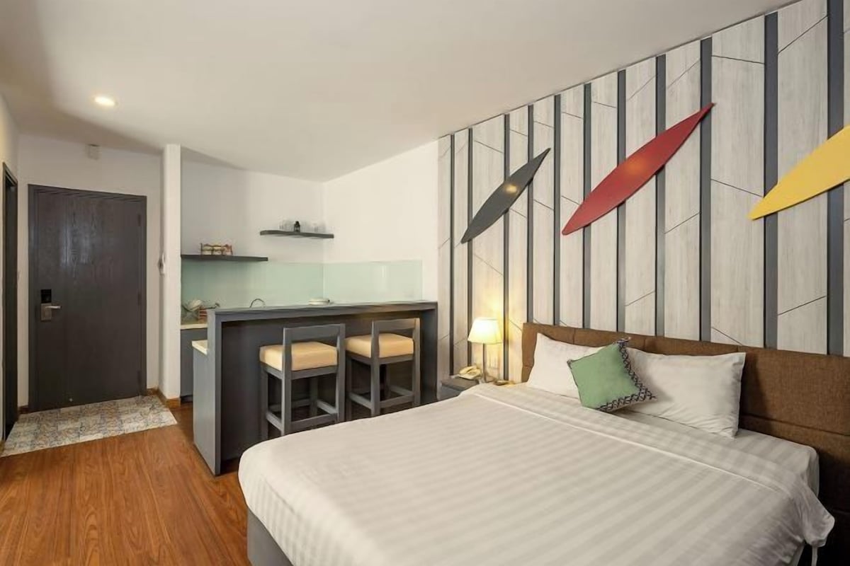 Een hotelkamer met een bed, een bureau en een kitchenette.