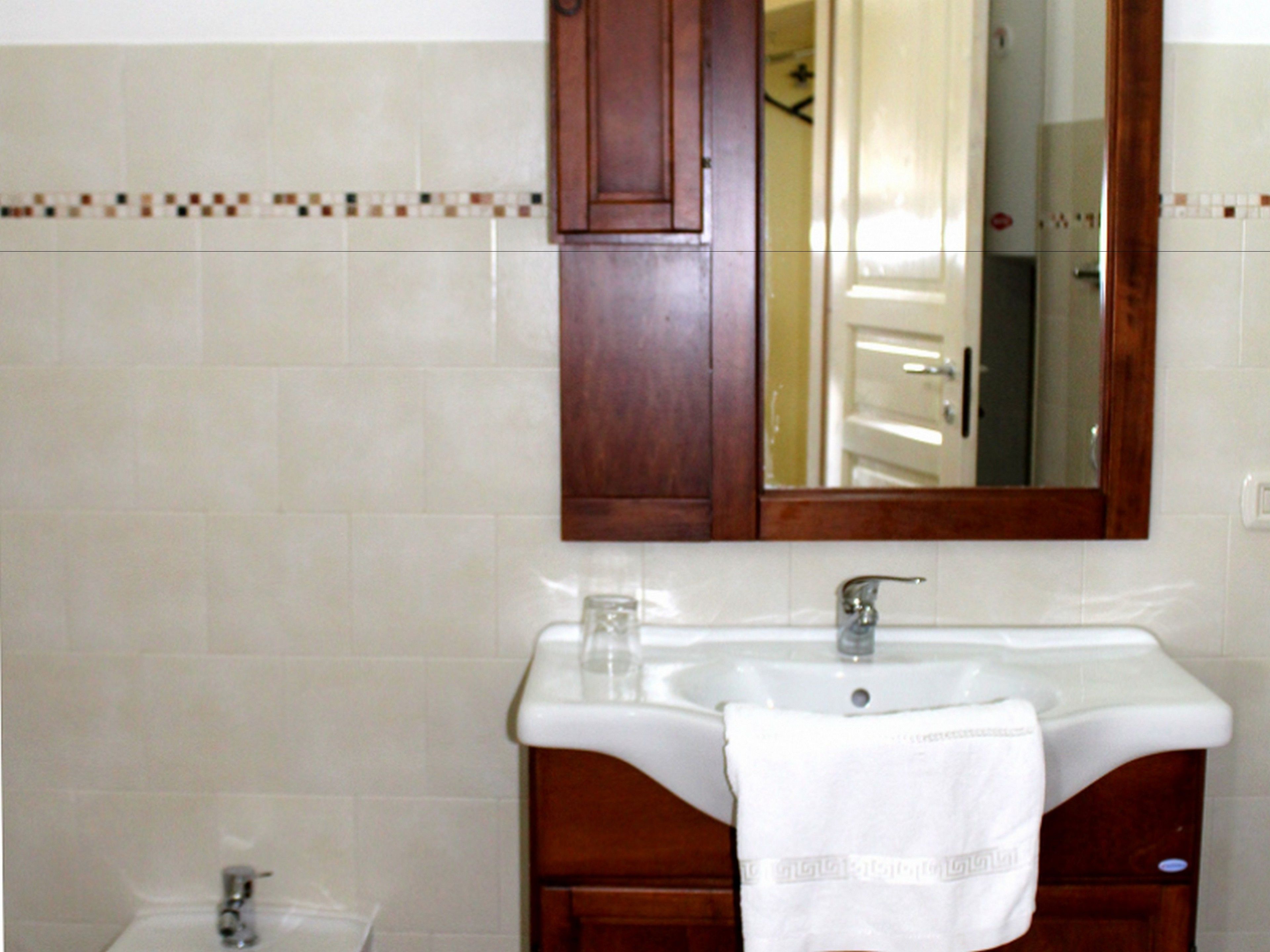 Un baño con un lavamanos blanco, un espejo y un armario de madera.
