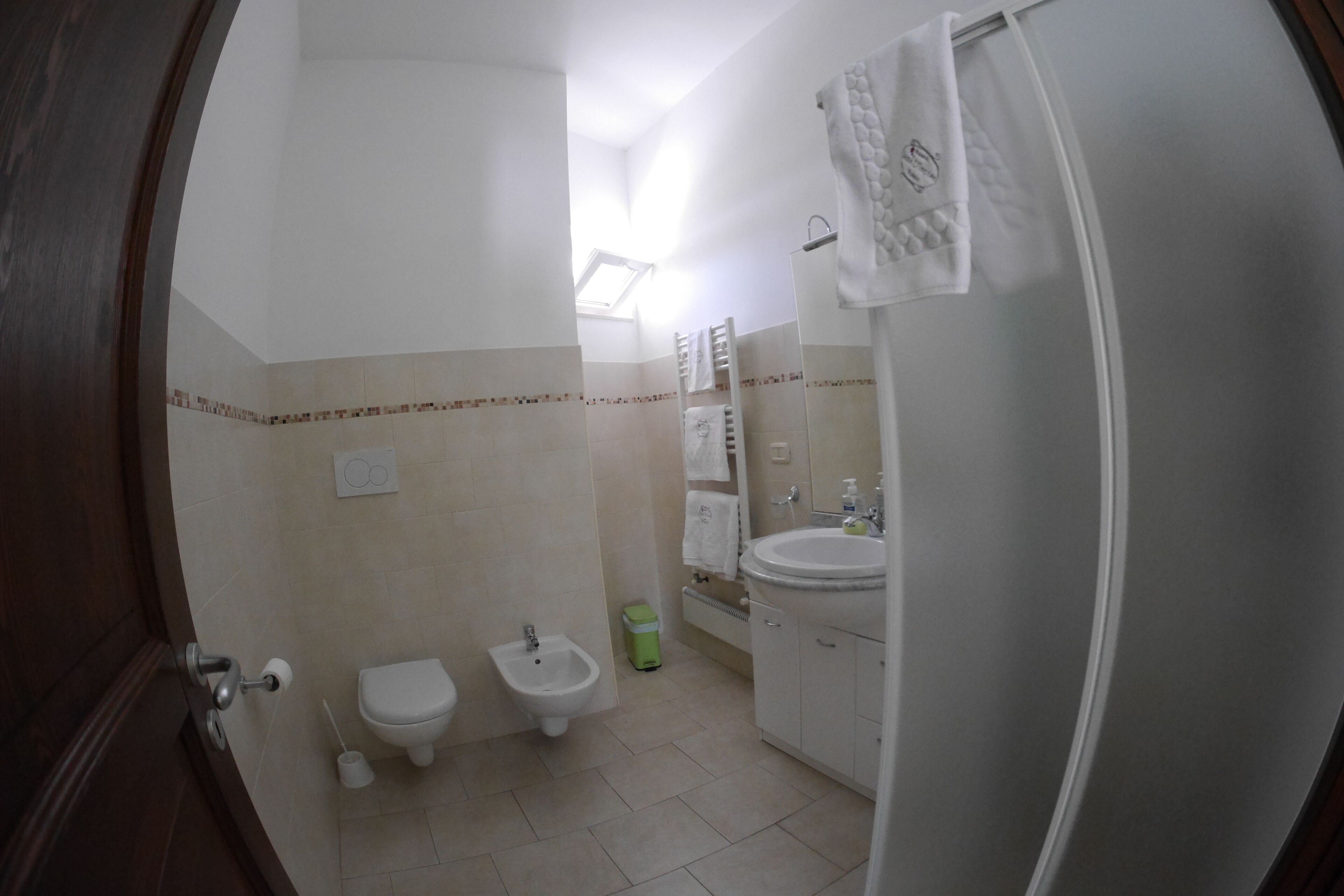 A bathroom with a toilet, bidet, sink, and mirror.
