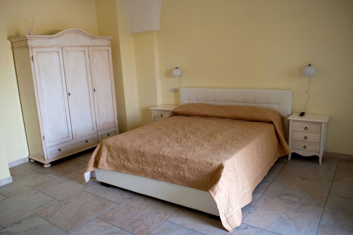 Una camera da letto con un letto, comodini, un armadio e una lampada a parete.