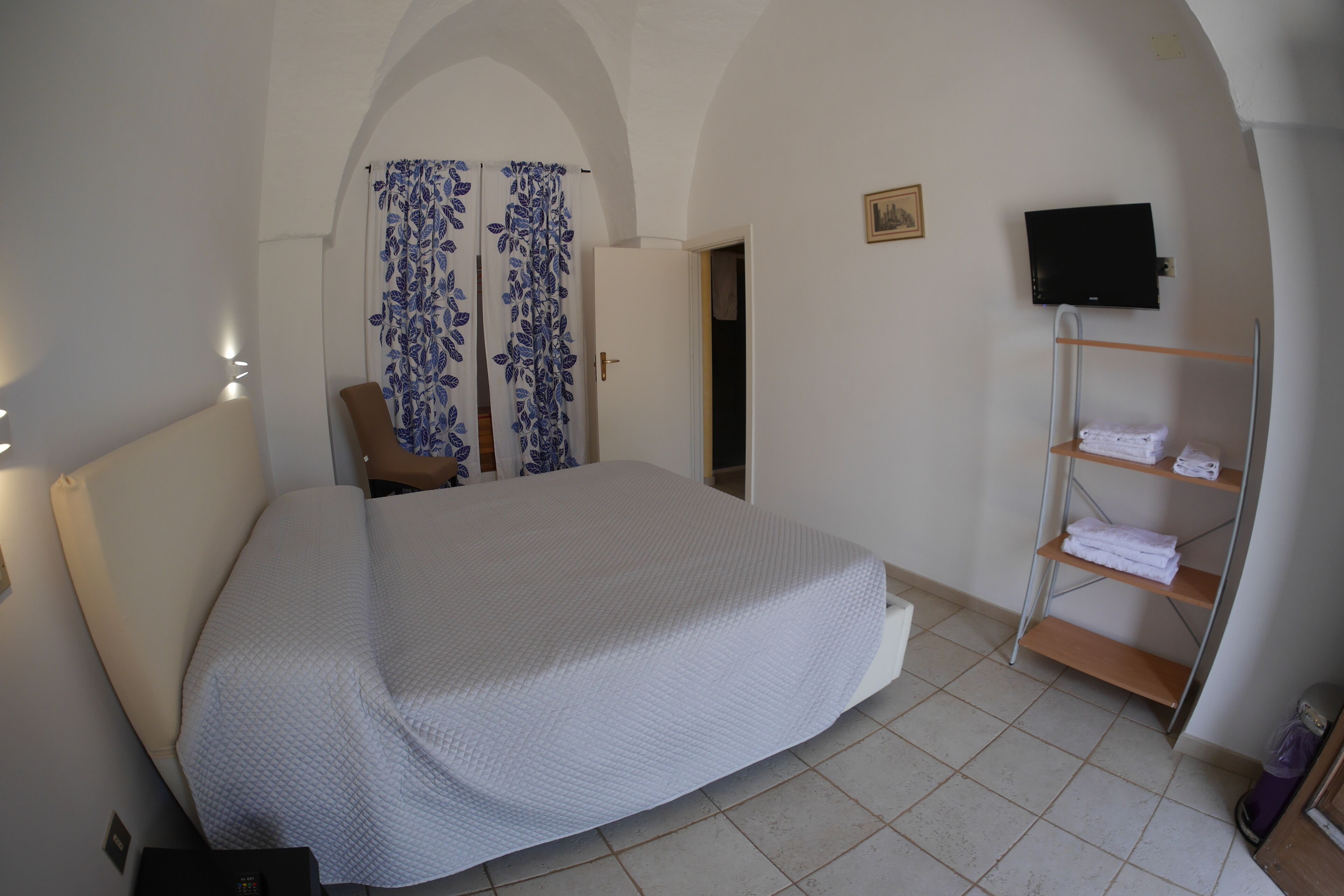 Ein Schlafzimmer mit Bett, Fernseher, Kleiderschrank und Duschbereich.