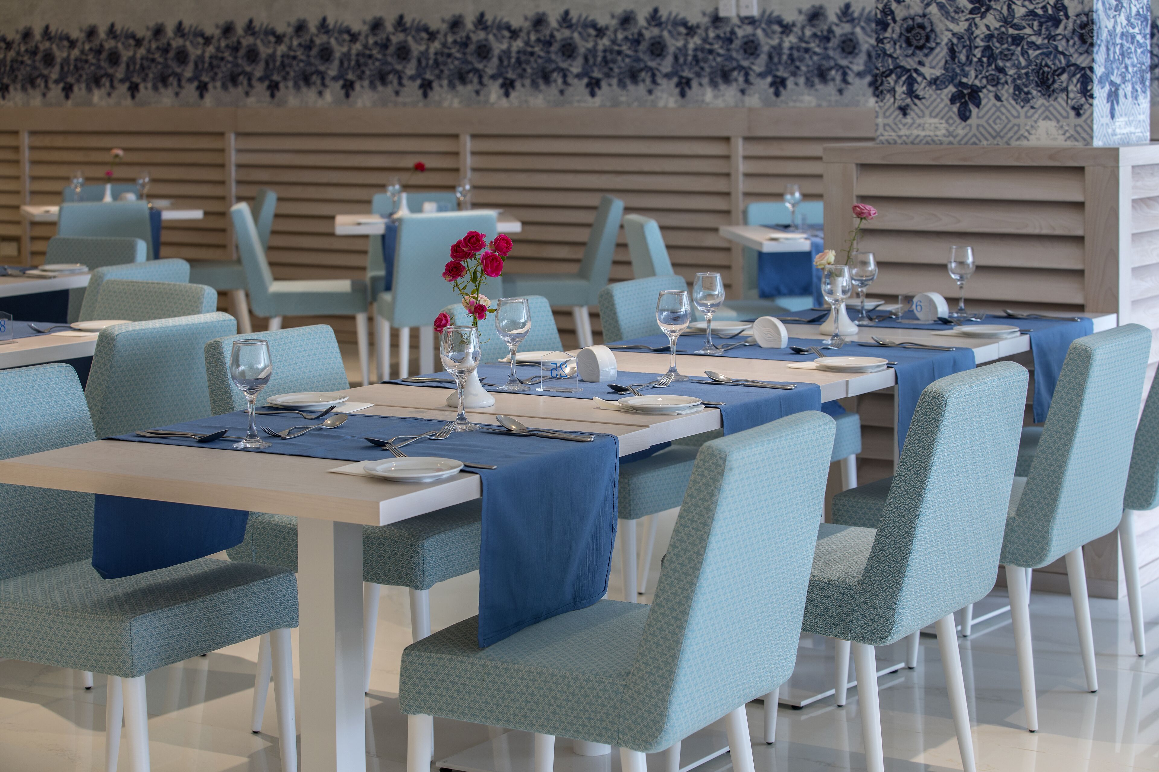 Un restaurante con mesas dispuestas para comer, con manteles y sillas azules a juego.