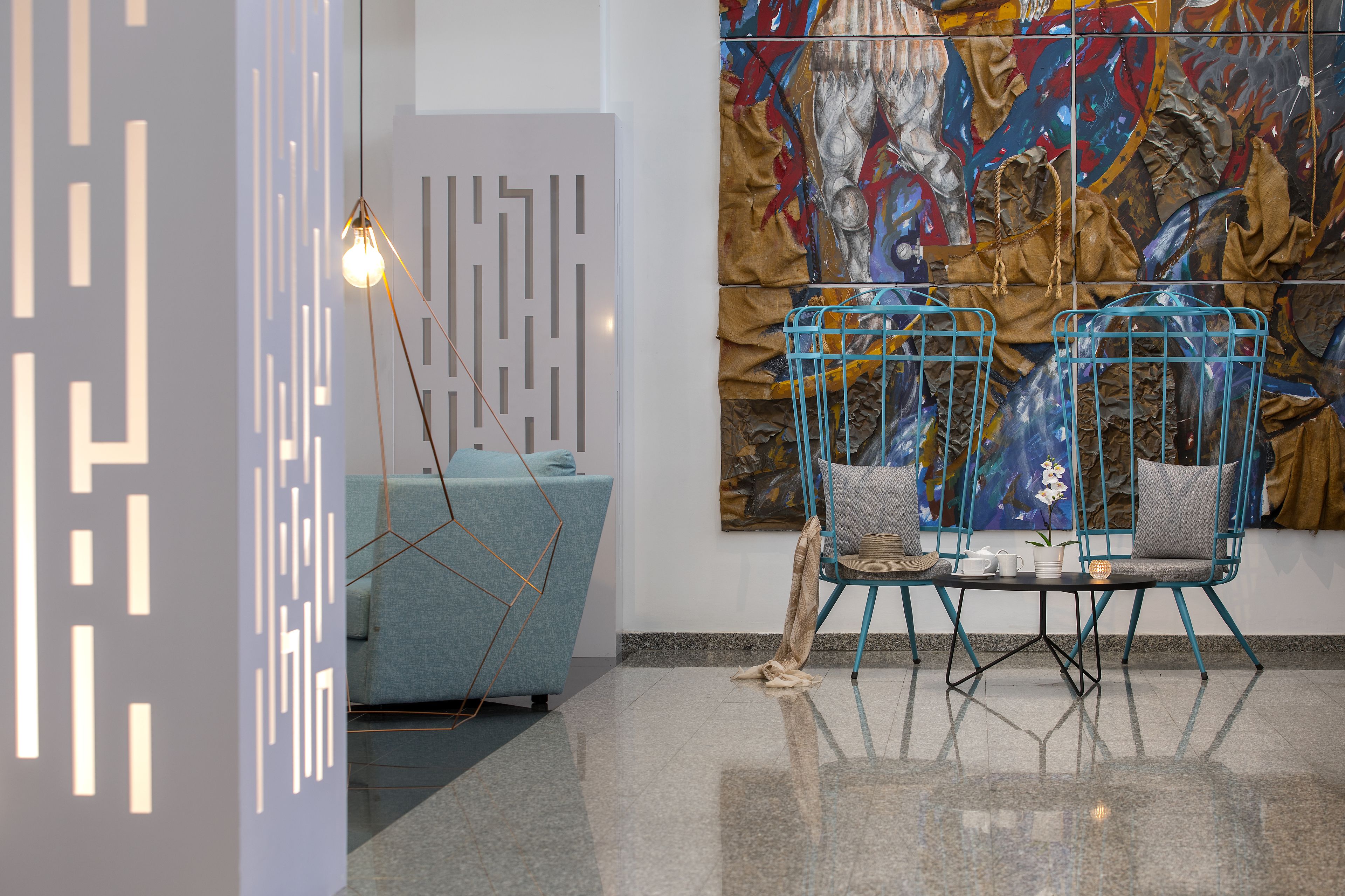 A modern interior with a geometric light fixture, a blue sofa, and a table with chairs.