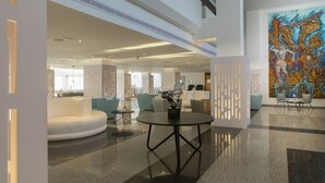Eine moderne Lobby mit einem runden Tisch, Sitzbereichen und einem großen abstrakten Gemälde.