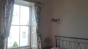 Un dormitorio con una cama, una ventana con cortinas y una decoración de pájaros en la pared.