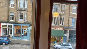 Une vue de la rue, prise à travers une fenêtre, d’un bâtiment dont la devanture est bleue et sur lequel on peut voir une enseigne indiquant « LEAF CO-OP ».