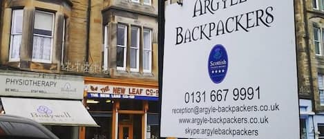 A sign for Argyle Backpackers with contact information and a Scottish logo.