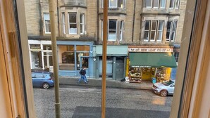 Une vue sur la rue, prise à travers une fenêtre, d’un immeuble où se trouve une boutique appelée « The New Leaf Co-op ».