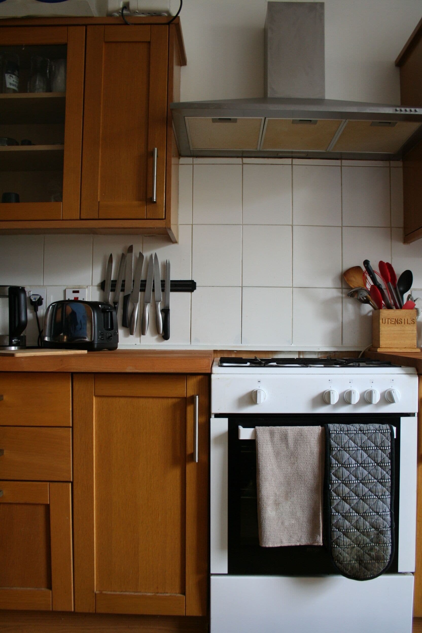A kitchen with wooden cabinets, a stove, and a knife rack.