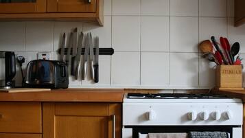 A kitchen with wooden cabinets, a stove, and a knife rack.