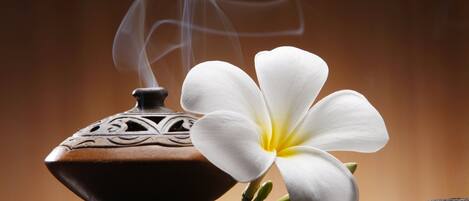 A white flower and a traditional incense burner on a stone surface.