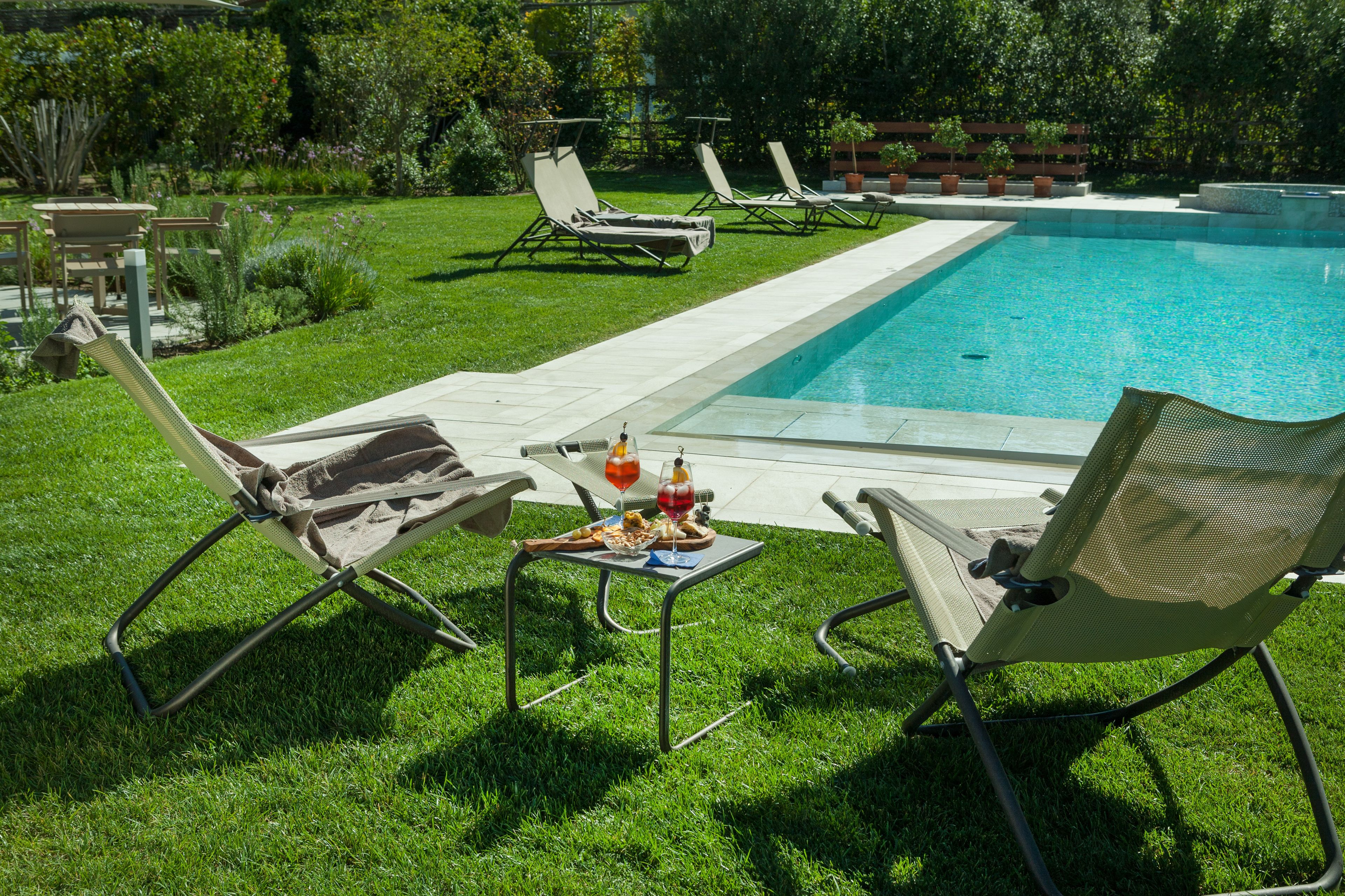 A poolside area with lounge chairs and a table with food and drinks.