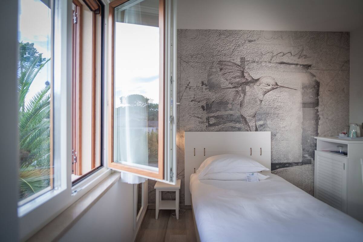 Un dormitorio con cama, ventana y pared con textura.