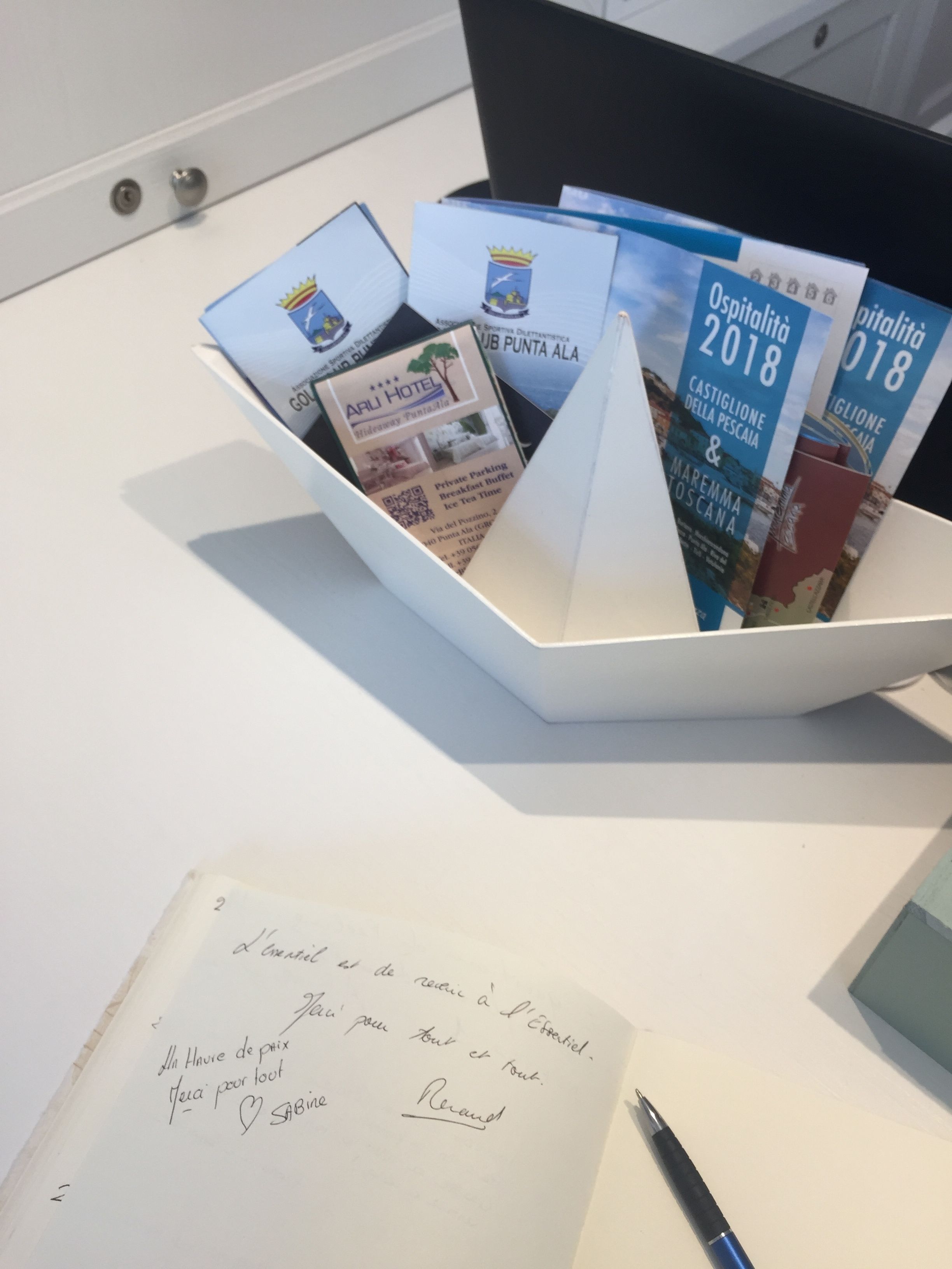 Een witte dienblad met brochures en een handgeschreven briefje op een bureau.