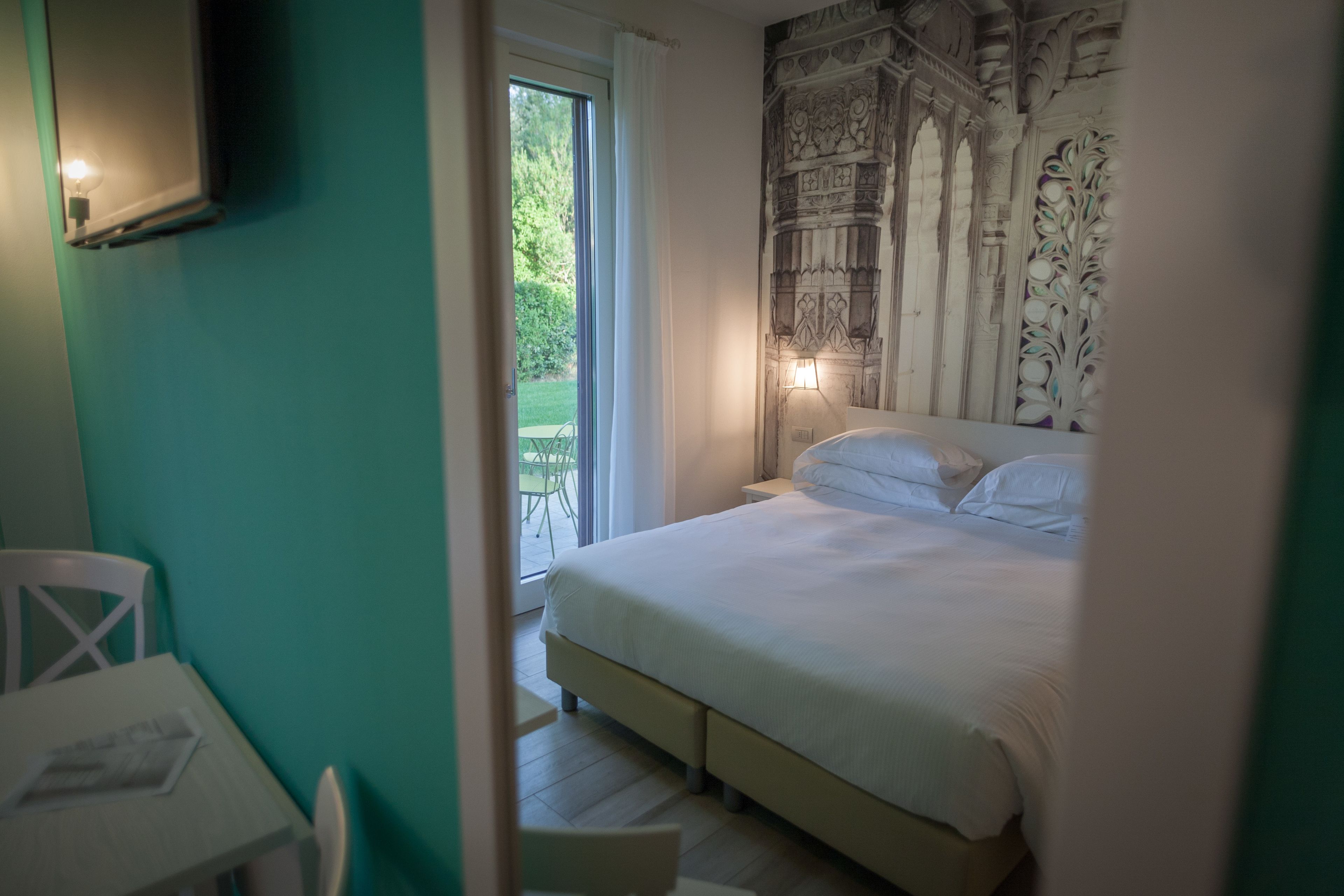 A bedroom with a bed, a nightstand, a chair, and a table.