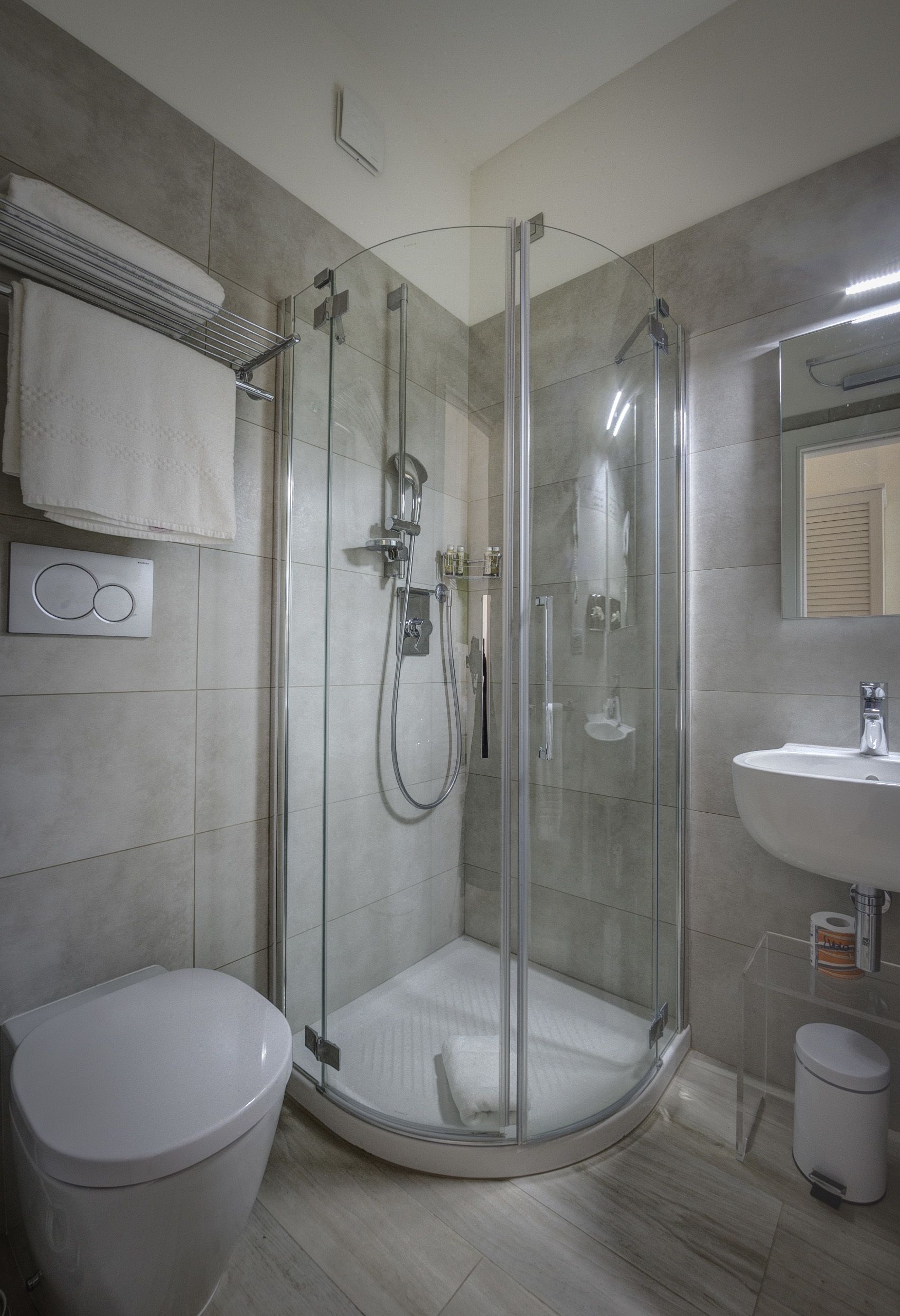 Un bagno moderno con doccia vetrata, un water bianco e un lavandino con specchio sopra.