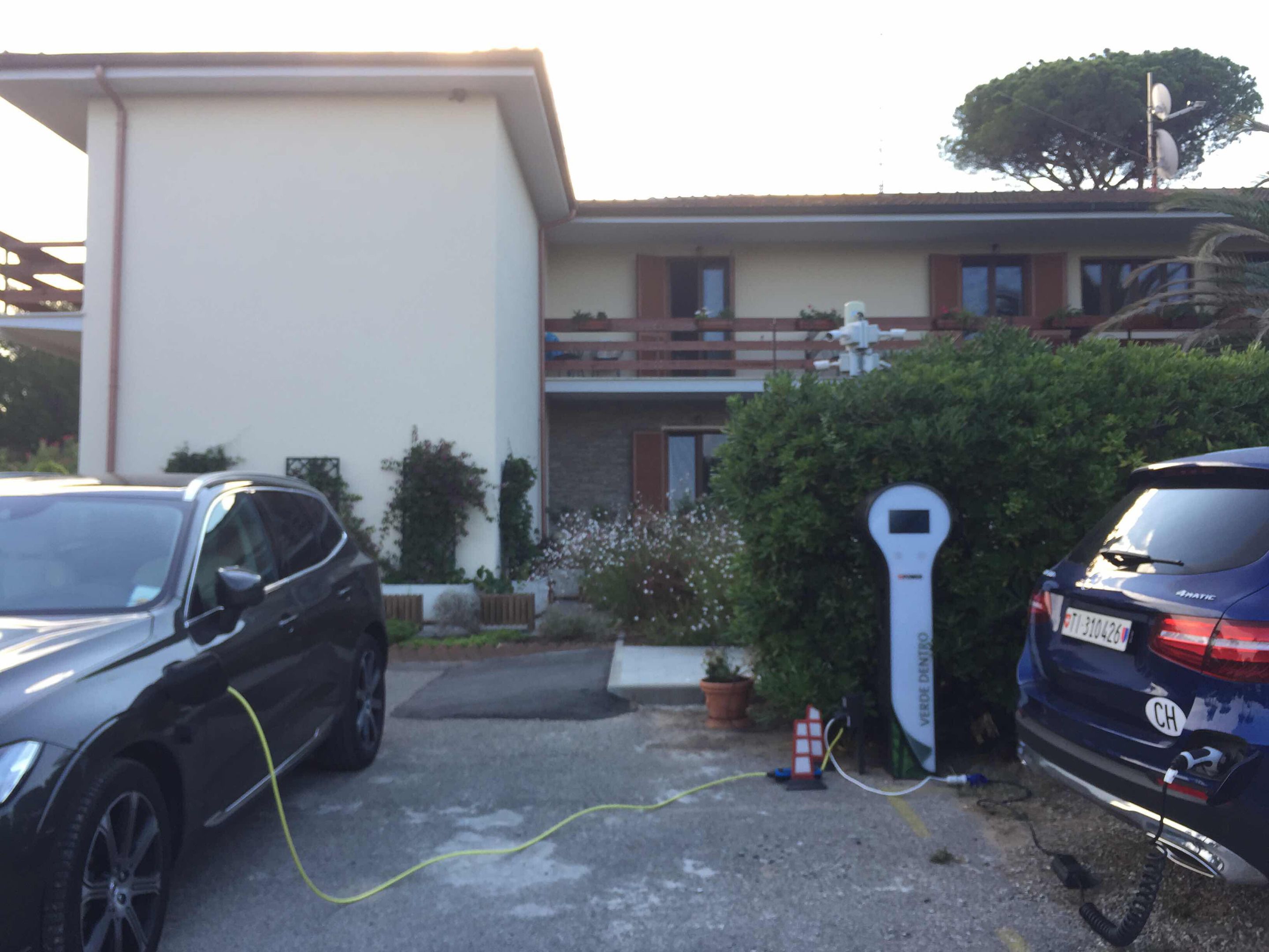 Two cars parked in a driveway with a parking meter and a small house-like structure in the background.