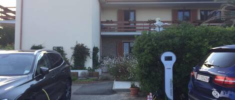 Two cars parked in a driveway with a parking meter and a small house-like structure in the background.